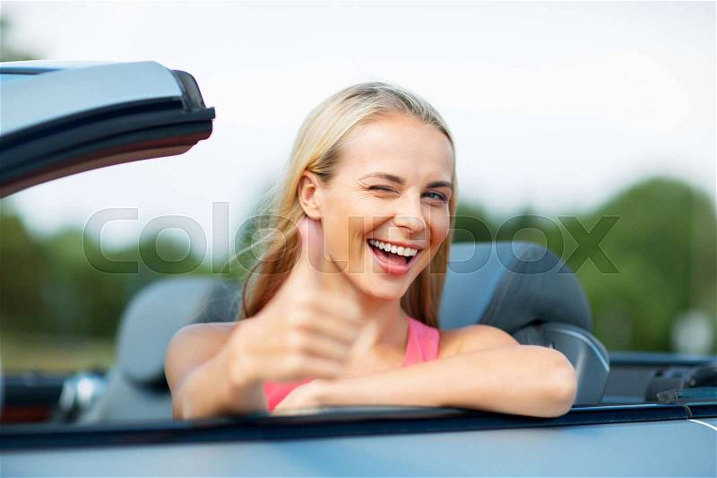 Travel, road trip and people concept - happy young woman showing thumbs up in convertible car, stock photo