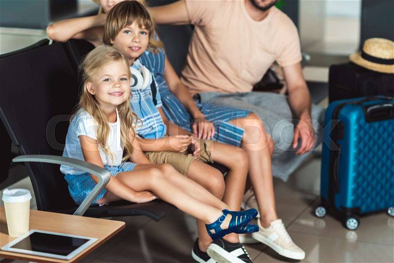 Young family waiting on seats for boarding at airport, stock photo