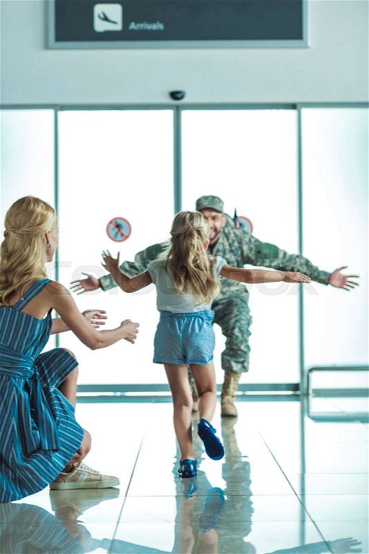 Happy little girl running to father in military uniform at airport, stock photo
