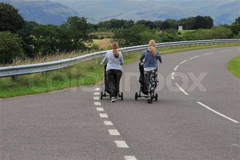 The two young mothers behind the buggy\'s are talking and walking over the viaduct to the village Stirling in Scotland in the summer, stock photo