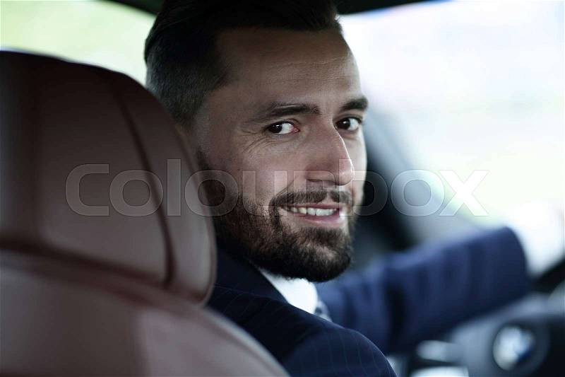 Close-up of a businessman sitting at the wheel of a car, stock photo