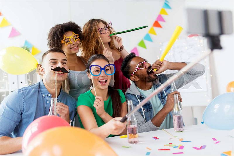 Corporate, celebration and holidays concept - happy friends or team with party accessories taking selfie at office, stock photo