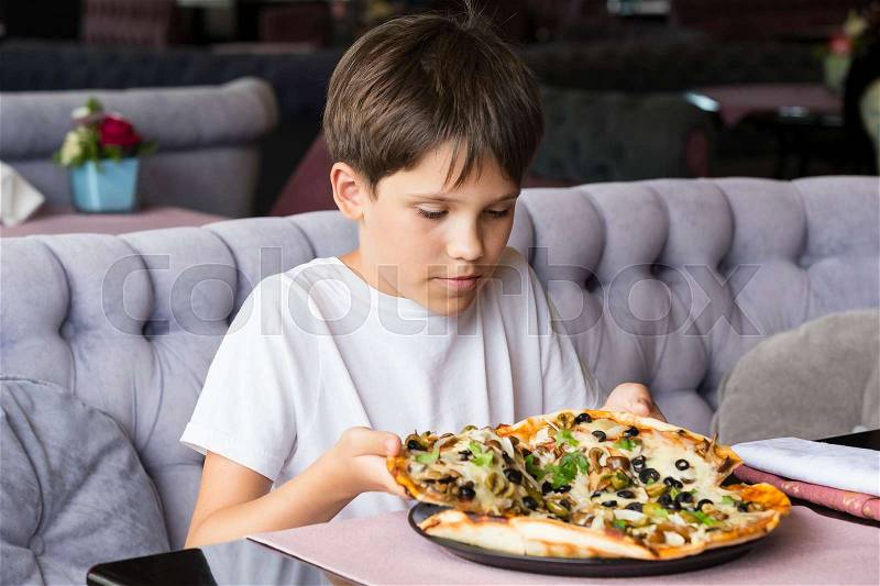 The boy is eating pizza in an Italian restaurant, stock photo