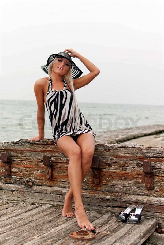 Girl in a hat sitting on a broken ship at sea, stock photo