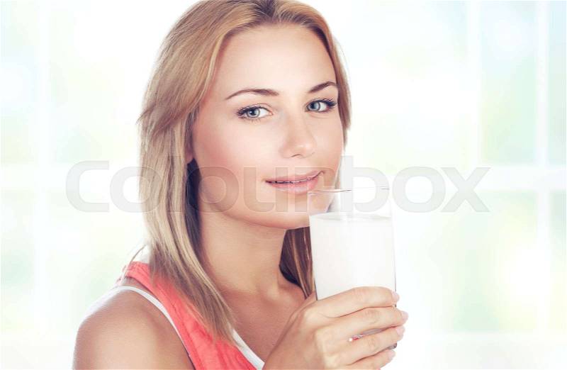 Portrait of a beautiful blond woman drinking milk at home, organic beverage for the breakfast, healthy nutrition concept, stock photo