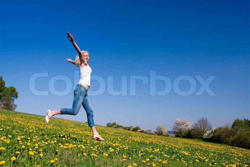 Young female having fun on flowery meadow, stock photo