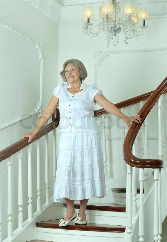 Portrait of beautiful elderly woman on stairs with railings, stock photo