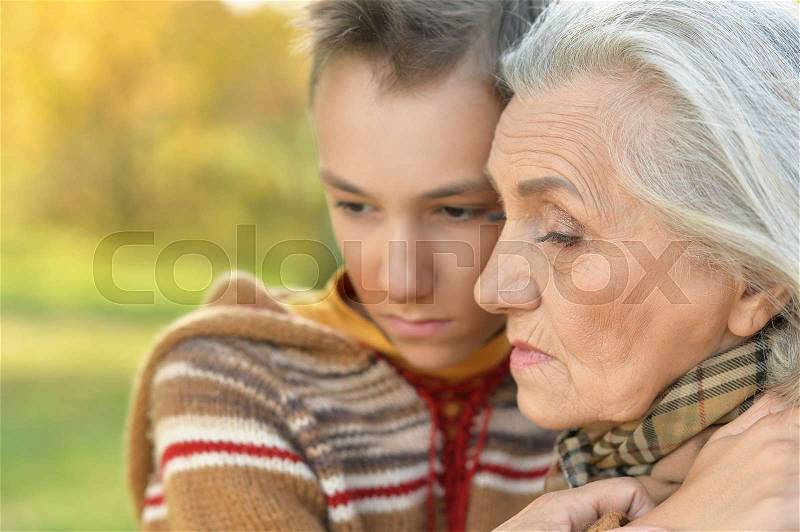 Sad grandmother and grandson hugging in park, stock photo