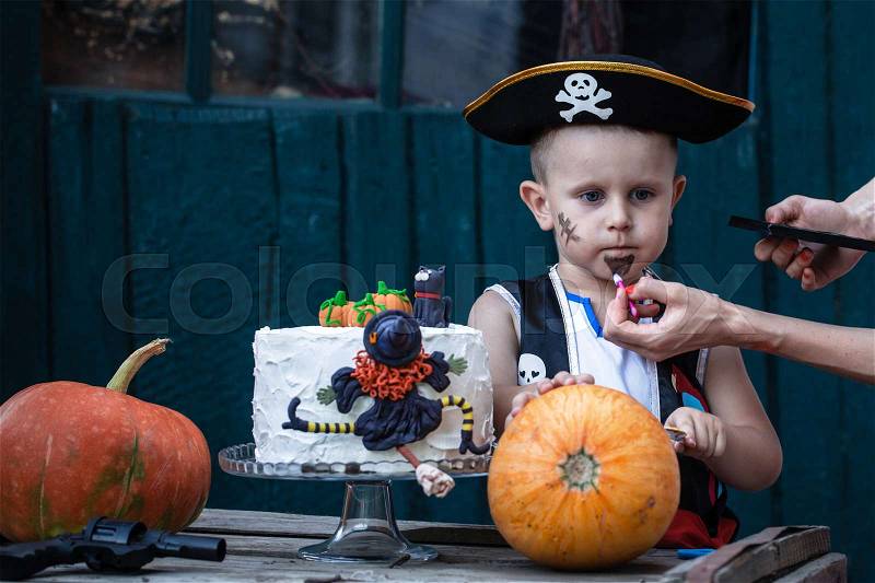 A little pirate with a pumpkin and a festive cake, stock photo