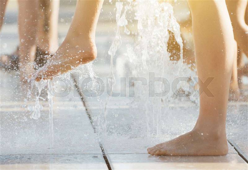 Woman having fun in small fountains at hot summer, stock photo
