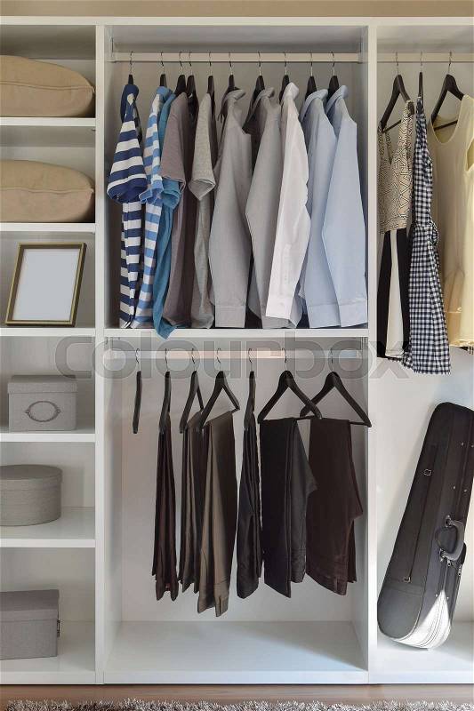 Modern closet with row of cloths hanging in white wardrobe, stock photo
