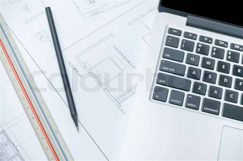 Black pencil and computer laptop on architectural drawing paper for construction, stock photo