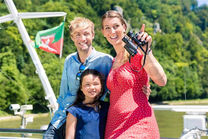 Family on river cruise with binoculars in summer enjoying their time, stock photo