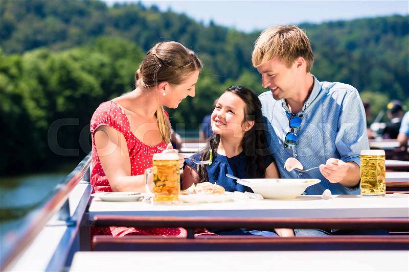 Family at lunch on river cruise with beer glasses on deck enjoying their time, stock photo