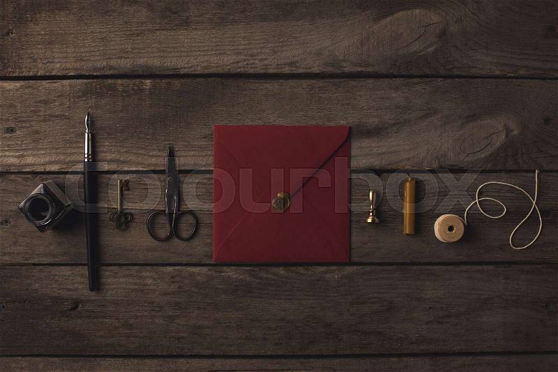 Composition of red envelope and decorative tools on rustic wooden table, stock photo