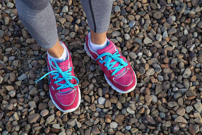 Pink sports shoes of woman on gravel, stock photo