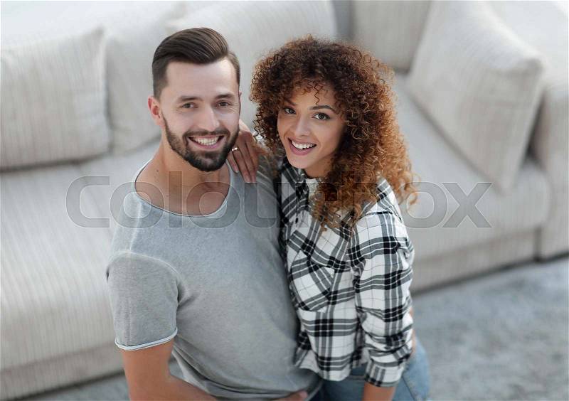 Young couple standing in new living room and looking at camera, stock photo