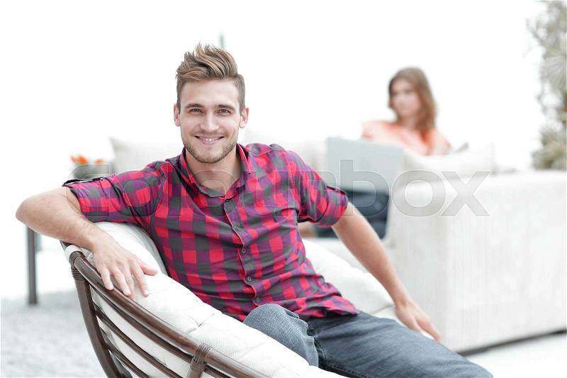 Young man sitting in the big chair in the living room blurry background, stock photo