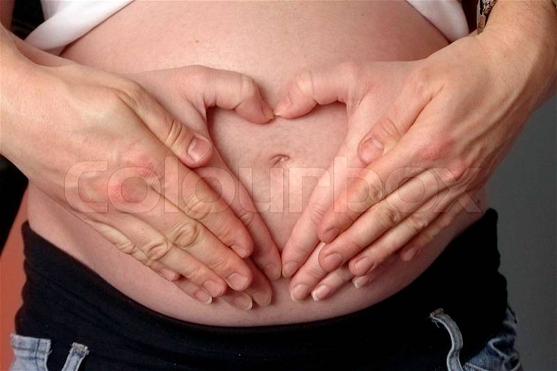 Heart from hands on belly gravid women, stock photo