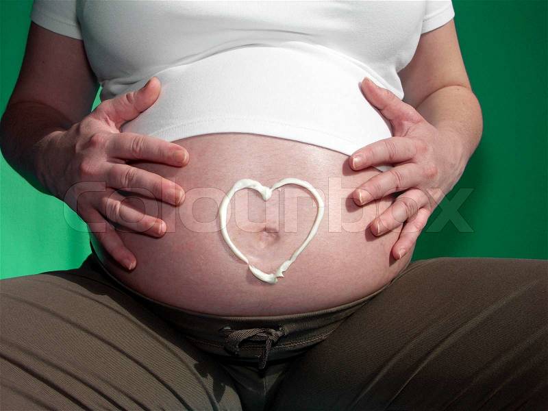 Painted heart from cream on belly gravid women, stock photo