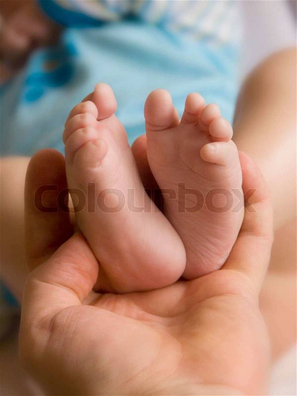 Soft holding her child's little feet, stock photo