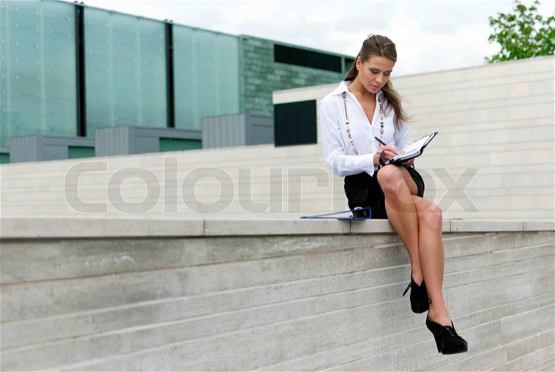 Business woman sitting in a black skirt and sign the document, stock photo