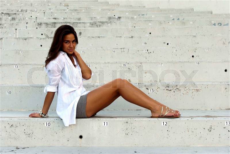 Girl in a white shirt sitting in an empty stadium, stock photo