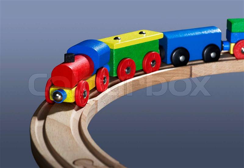 Studio photography of a colorful wooden toy train in dark bluish back, stock photo