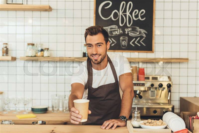 Portrait of smiling barista putting coffee to go on counter in cafe, stock photo