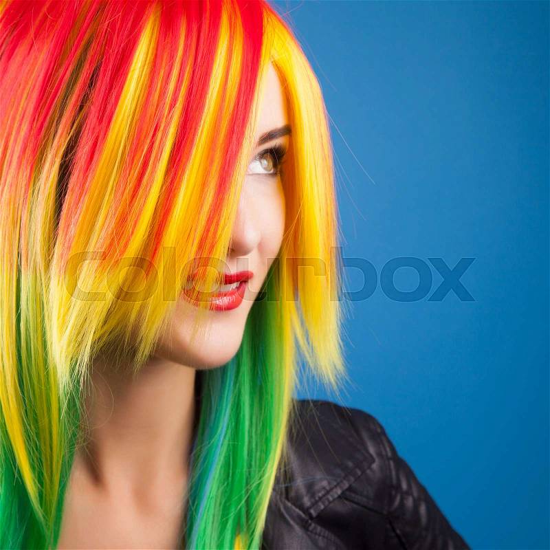 Beautiful woman wearing color wig against blue background, stock photo