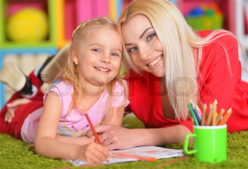 Happy mother draws with her little daughter, stock photo