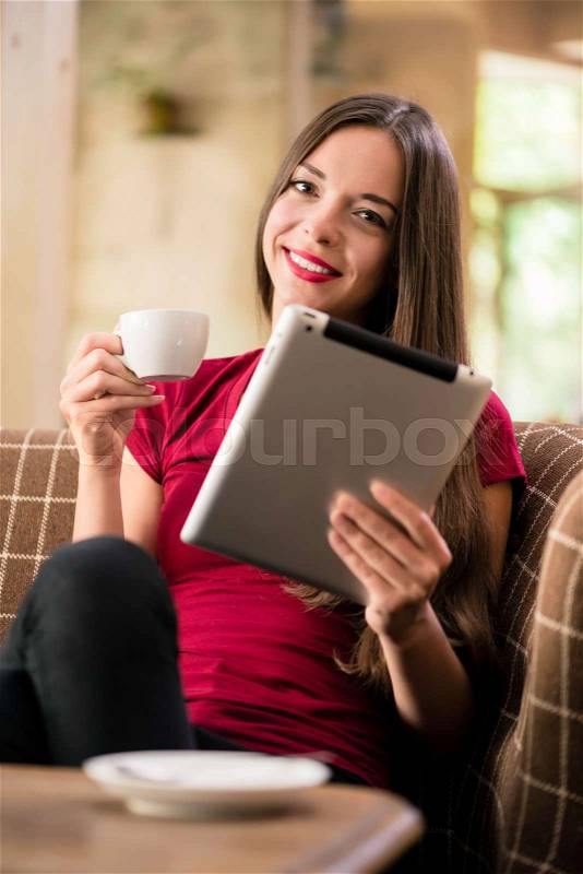 Contemporary young woman reading on tablet in a coffee shop or cafe, stock photo