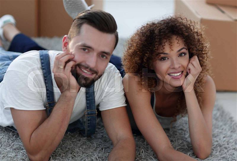 Married couple lying on the floor after moving. Housing and investment, stock photo