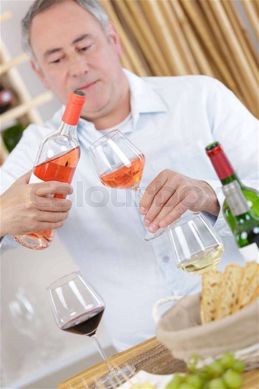 Happy man with a glass of rose wine at home, stock photo
