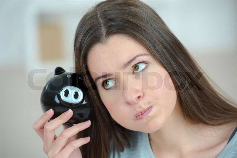 Woman looking weird holding a piggy bank, stock photo