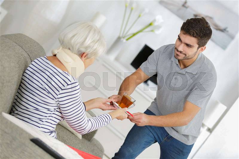 Elder woman taken care of by young man, stock photo