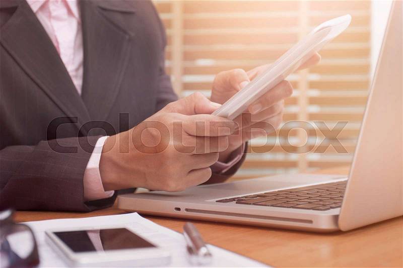 Business woman using tablet computer on desk at work, stock photo