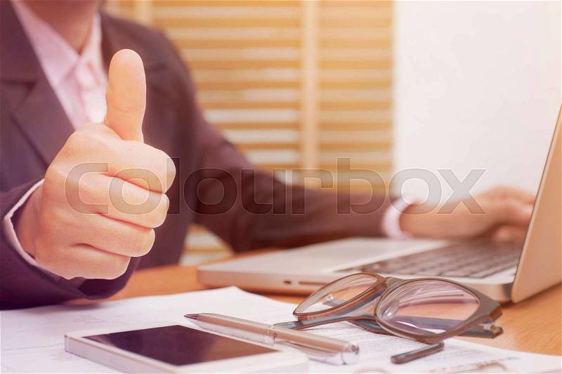 Business woman thumbs up while working with laptop computer. , stock photo