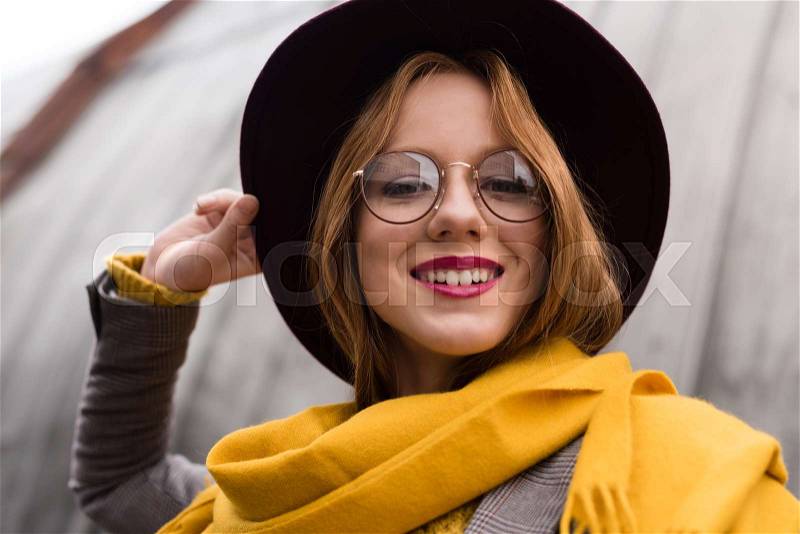 Beautiful stylish smiling redhead girl in eyeglasses, fedora hat and yellow scarf , stock photo