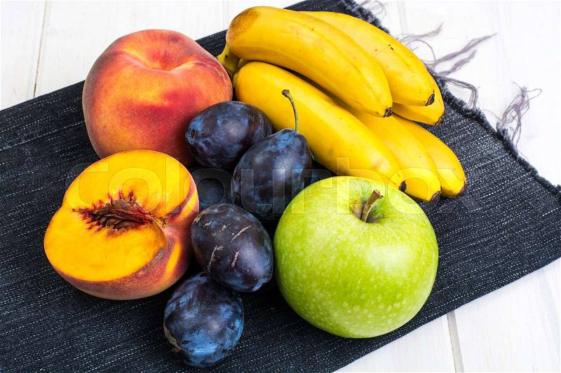 Assorted ripe fresh plums, bananas, peaches and apples on white table. Studio Photo, stock photo