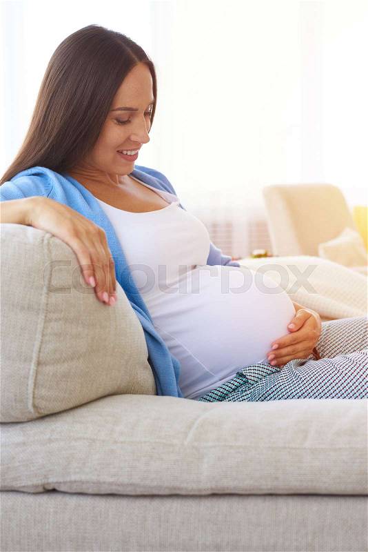 Side view of delicate mother keeping hands on belly. Concept of maternity , stock photo
