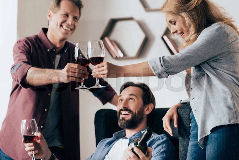 Happy middle aged friends clinking glasses of wine and celebrating together, stock photo