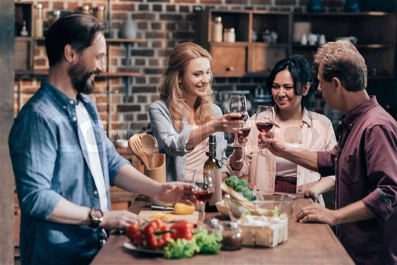 Happy multiethnic friends drinking wine and cooking dinner together, stock photo