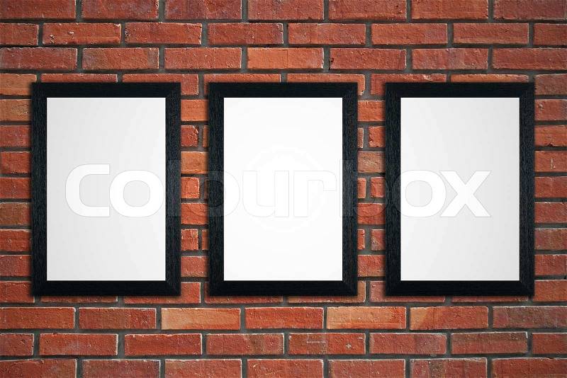 Three black picture frames on red brick wall, stock photo