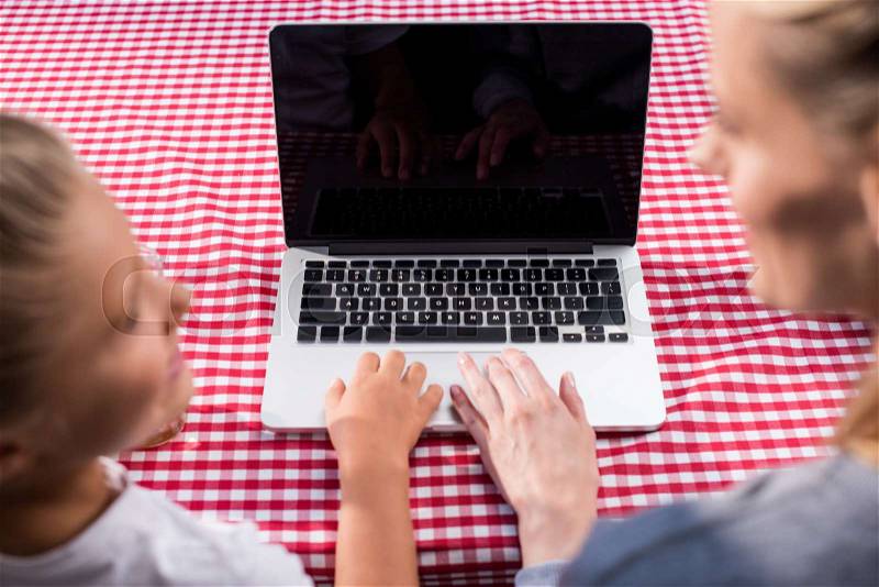 Cropped shot of mother and preteen daughter using laptop together at home, stock photo