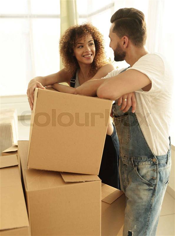 Happy couple standing near boxes in their new apartment. The concept of moving, stock photo