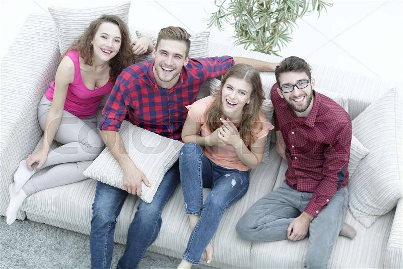 View from the top.the four friends laugh, sitting on the sofa, stock photo