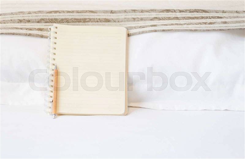 Blank notbook and wood pencil on white bed, stock photo