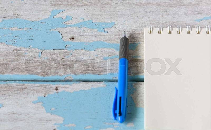 Workspace notebook and blue pen on vintage white wooden table background, stock photo