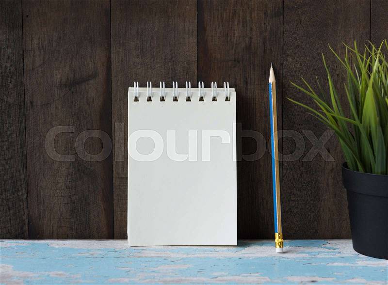 Workspace notebook and yellow pencil on vintage blue wooden table background, stock photo